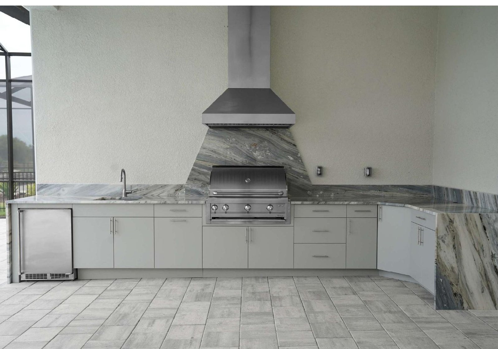 TrueSpec HDPE outdoor kitchen cabinetry installed on a covered patio with stone-look countertop, grill, and undercounter refrigerator